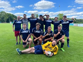 Das Bild zeigt 12 junge Männer in dunkelbleuen Fußballtrikot mit dem weiß hinterlegten Logo des utg. Die Personen schauen alle in die Kamera. Sie stehen als Mannschaft in drei reihen gruppiert auf einem Fußballrasen.
