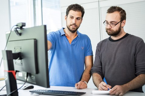 Zwei Mitarbeiter diskutieren am Bildschirm
