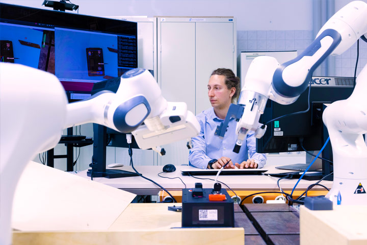 A scientist works with two industrial robots